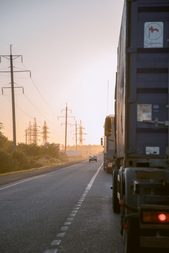 about-us Trucks on a highway during sunset with power lines, creating a serene yet industrial scene.